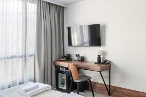 a room with a desk with a television and a chair at AIRINN Vilnius Airport Hotel RENOVATED 2025 in Vilnius