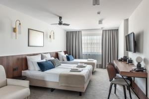 a living room with two beds and a table and a couch at AIRINN Vilnius Airport Hotel RENOVATED 2025 in Vilnius