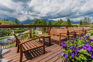 a row of benches on a deck with flowers at Hotel Lesana in Vysoké Tatry
