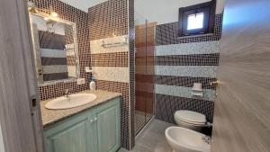 Un baño con lavabo, inodoro y espejo. en Casa Grazia Deledda, en Orosei