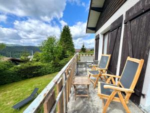 a porch with two chairs and a table at Grand chalet de charme cosy, sauna & vue de rêve in Ban-sur-Meurthe-Clefcy