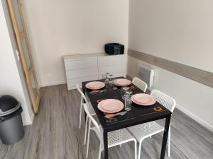 a dining room table with pink plates and chairs at Studio meublé centre ville- gare Villers Cotterets in Villers-Cotterêts