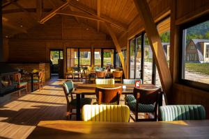 a restaurant with tables and chairs and windows at Altus Highland Lodges in Tepelenë