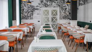 a dining room with white tables and orange chairs at Cardinal in Quba