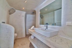 a bathroom with a sink and a toilet and a mirror at Armeni Village in Oia