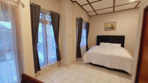 een slaapkamer met een bed en een groot raam bij Agni Homestay in Timuran +9 foto's