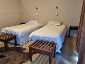 twee bedden in een kamer met twee tafels en een bank bij Cookhouse Cottages in Vosburg
