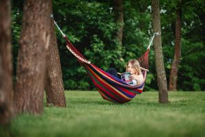 a girl laying in a hammock in a park at Hotel Młyn Aqua Spa Biblioteka in Elblag