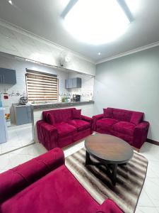 a living room with red couches and a table at Hadraj Moshono Apartment2 in Arusha +1 photo