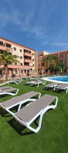 a group of lounge chairs on the grass near a building at Enebrales 423 in Punta Umbría