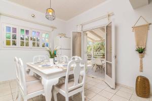 a white dining room with a white table and chairs at Villa La Onta by Villa Plus in Makris Gialos