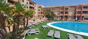 a hotel with a swimming pool and lounge chairs at Enebrales 304 in Punta Umbría