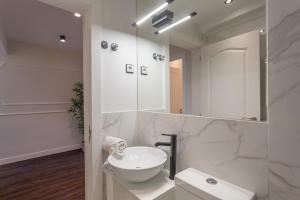 a white bathroom with a sink and a mirror at BeGuest Casa dos Poetas Oeiras Apartment in Oeiras +18 photos