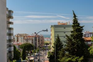 a city street with a tall tree in the foreground at BeGuest Casa dos Poetas Oeiras Apartment in Oeiras