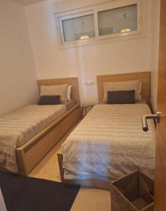 two beds in a small bedroom with a window at Casa Émir in Roldán +20 photos