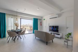 a living room with a table and chairs and a television at Stylish Side Seaview Penthouse By Quicktrips in St. Paul's Bay