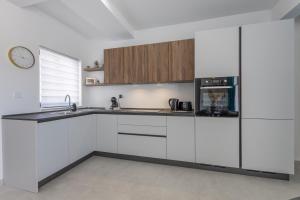 a kitchen with white cabinets and a clock on the wall at Stylish Side Seaview Penthouse By Quicktrips in St. Paul's Bay