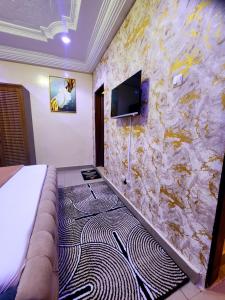 a bedroom with a stone wall with a couch and a tv at Studio meublé avec toute les commodités dans le quartiers et environs in Dakar