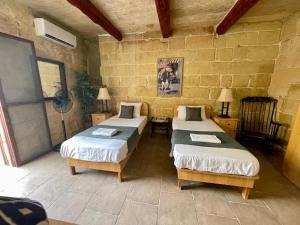 a room with two beds and a stone wall at Pretty Villa & Private Pool in Għajnsielem