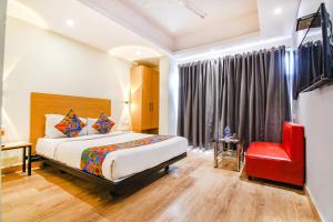 a bedroom with a bed and a red chair at FabHotel Suncitel - Nr Netaji Subhash Chandra Bose International Airport in Kolkata