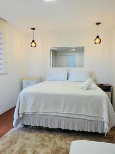 a bedroom with a large white bed with a mirror at Bangalô Miraflores in Chapada dos Guimarães