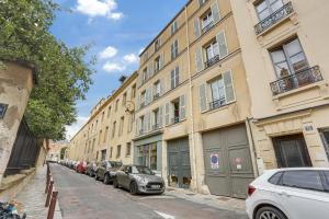 eine Reihe von Autos, die auf einer Straße neben Gebäuden geparkt sind in der Unterkunft Le Marquiis-Versailles in Versailles