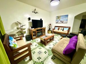 a living room with a couch and a tv at Kasa Mandulia Beachfront House in Lobo
