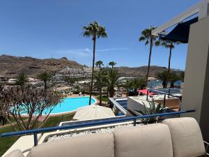 Un sofá sentado en un balcón junto a una piscina. en Lovisi Suite Playa del Cura - OCEAN & POOL VIEW, en Mogán
