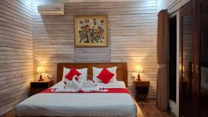 a bedroom with a bed with red and white pillows at Oka Cottage in Nusa Penida