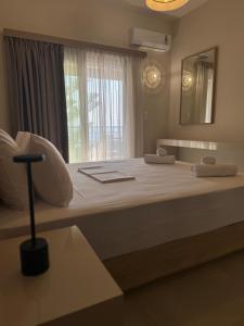 a large white bed in a room with a window at AGALI ROOMs in Perdika