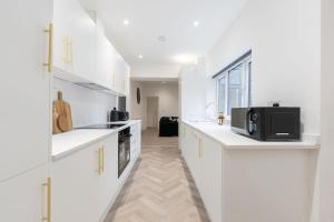 a white kitchen with white cabinets and a microwave at Luxury Stay by City Centre Etihad and COOP Live in Manchester