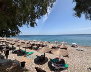 a beach with many chairs and umbrellas and the ocean at Mare Calmo Studios, Chios in Chios