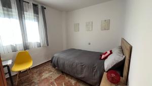 a bedroom with a bed and a yellow chair at Apartamento en Almuñécar con piscina comunitaria in Almuñécar +19 photos