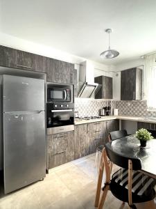 a kitchen with a stainless steel refrigerator and a table at Modern and family-friendly apartment in Birkhadem in Birkhadem