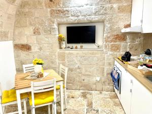 a kitchen with a table and a tv on a stone wall at Antica Pietra in Polignano a Mare