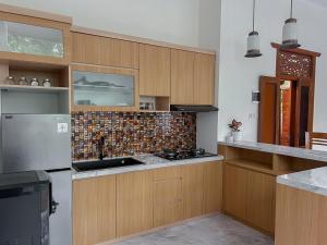 een keuken met houten kasten en een kookplaat met oven bij Gee Villas Yogyakarta in Ngingas +5 foto's
