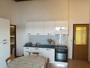 a kitchen with white cabinets and a table and a sink at On the beach apartments PAG in Dinjiška