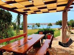 a wooden picnic table and hammock under a pergola at On the beach apartments PAG in Dinjiška