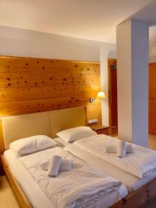 two beds in a bedroom with a wooden headboard at Goldenhof in Auer