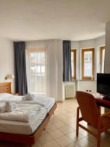 a bedroom with a bed and a desk and a television at Goldenhof in Auer
