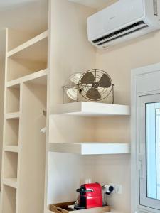 Una cocina con estantes blancos y un ventilador. en LIV Aspropyrgos, en Asprópirgos 30 fotos más