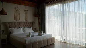 a bedroom with a white bed with a large window at Hotel Natali in Dhërmi