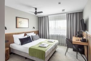 a hotel room with a bed and a desk and a television at AIRINN Vilnius Airport Hotel RENOVATED 2025 in Vilnius
