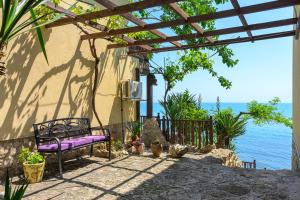 a purple bench sitting under a pergola next to the water at Morski Briag Hotel in Golden Sands