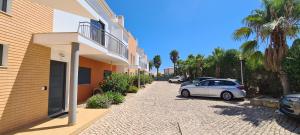 une voiture blanche garée à côté d'un bâtiment avec des palmiers dans l'établissement Jardins de Pera vila M, à Pêra