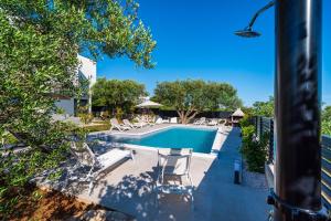 a swimming pool with lounge chairs next to a house at Apartment Vista Mare 1 with heated pool in Sveti Filip i Jakov
