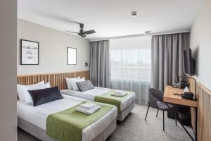 a hotel room with two beds and a desk at AIRINN Vilnius Airport Hotel RENOVATED 2025 in Vilnius