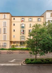 a building with a tree in front of a street at Chic appartement, coeur de Saint Tropez, Place des Lices in Saint-Tropez
