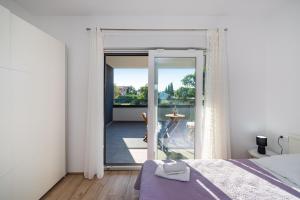 a bedroom with a bed and a view of a balcony at Apartment Vista Mare 1 with heated pool in Sveti Filip i Jakov +42 photos