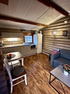a kitchen and a living room with a couch and a table at Grasbakken hytteutleie in Nesseby